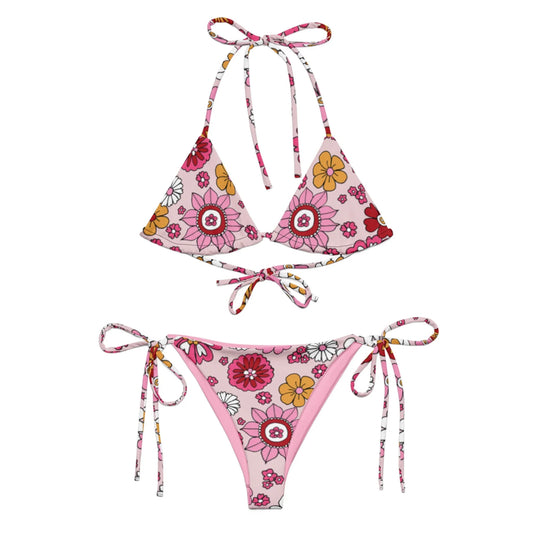The Adriana String Bikini Swimsuit by Printful features a pink, floral pattern in red, yellow, and white. This women’s set includes a triangle top and side-tie bottoms made from recycled polyester with UPF 50+ protection.