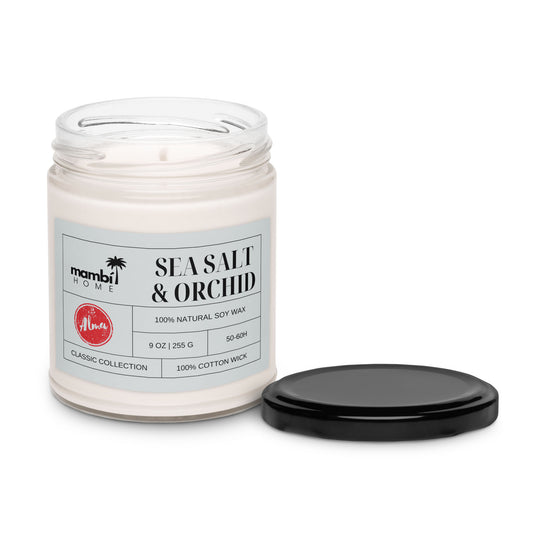 A glass jar candle labeled mambi HOME Sea Salt & Orchid, made with 100% natural soy wax for a long burn time. This 9 oz scented soy candle features a 100% cotton wick, and the black lid rests beside the jar on a white background.