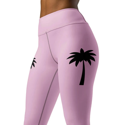 Model wears Printfuls Alpine High-Rise Yoga Leggings for women in pink, featuring black palm tree graphics on each thigh, styled between waist and mid-thigh for a trendy athleisure look.