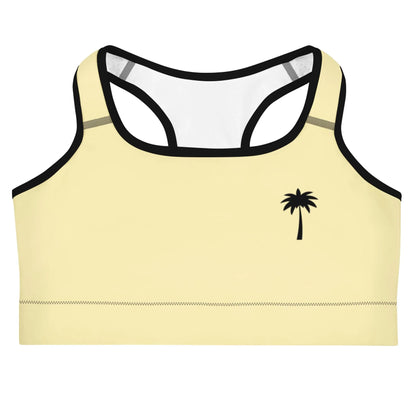 A light yellow Mambí sports bra with black trim and a small black palm tree graphic on the left side. It features a racerback design and visible stitching along the bottom edge.