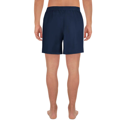 A person stands barefoot facing away in Printful Belmar Long Athletic Shorts | Unisex, navy blue with an elastic waistband for comfort and performance, ideal for running. The background is plain white.