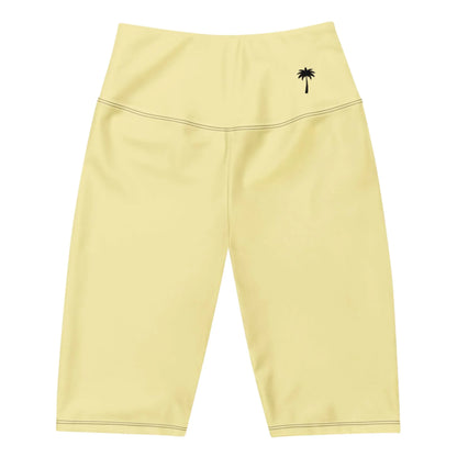 Light yellow Mambí high-waisted biker shorts featuring a small black palm tree graphic on the left hip area, displayed on a white background.