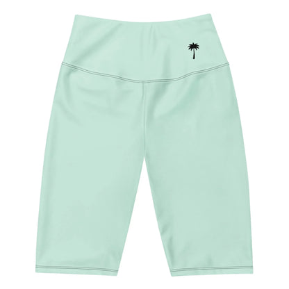 Light green, high-waisted, knee-length athletic shorts featuring a small black palm tree graphic on the waistband’s left side. These Mambí shorts have smooth fabric and visible stitching.