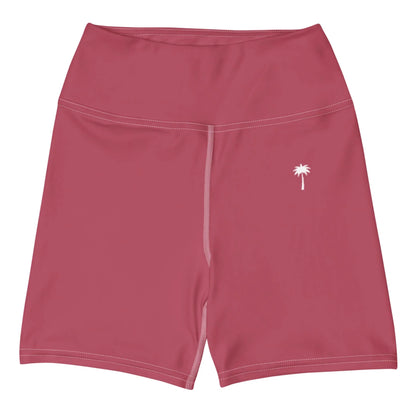 The Printful Brickell Yoga Shorts for women are high-waisted pink shorts featuring a high waistband, visible white seam stitching, and a small white palm tree graphic on the left thigh.