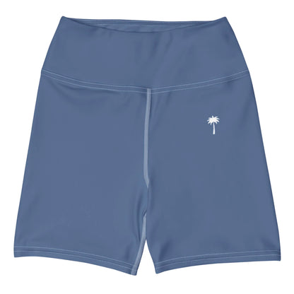 The Brickell Yoga Shorts by Printful feature a blue high-waist design, white stitching, a small white palm tree on the left thigh, and four-way stretch for comfort. Displayed on a plain white background.