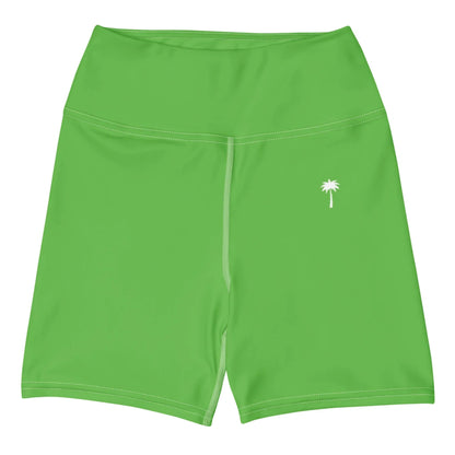 The Printful Brickell Yoga Shorts for women are bright green, high-waisted, with four-way stretch and a small white palm tree graphic on the left thigh, shown against a plain white background.