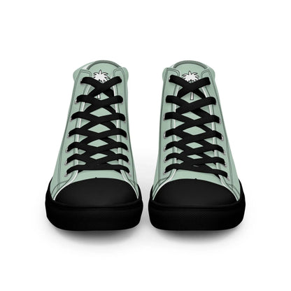 A pair of high-top Mambí sneakers with light green sides, black laces, black toes and soles, and a white palm tree graphic on each tongue, shown from the front against a white background.