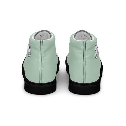 A pair of mint green Mambí high-top sneakers with black soles, shown from the back. Each shoe features a circular white and black logo near the heel.