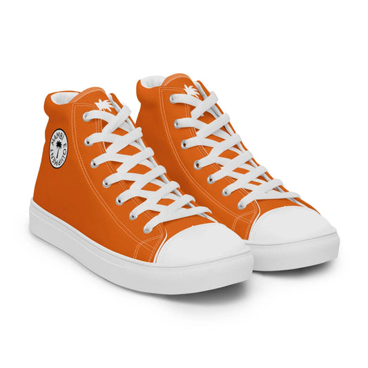 A pair of bright orange high-top Mambí sneakers with white laces, white soles, and a circular black-and-white palm tree logo on the ankle area.