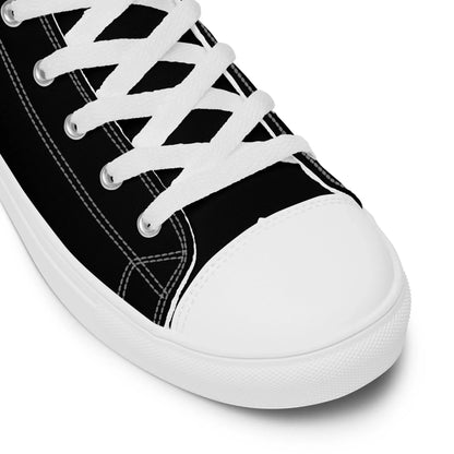 A close-up of the Carlito Sastre Vintage Hi-Top Sneakers by Printful for women in white/black, featuring white laces, stitching, and a rubber toe cap and sole. The shoe is angled from above, displaying its side and front.