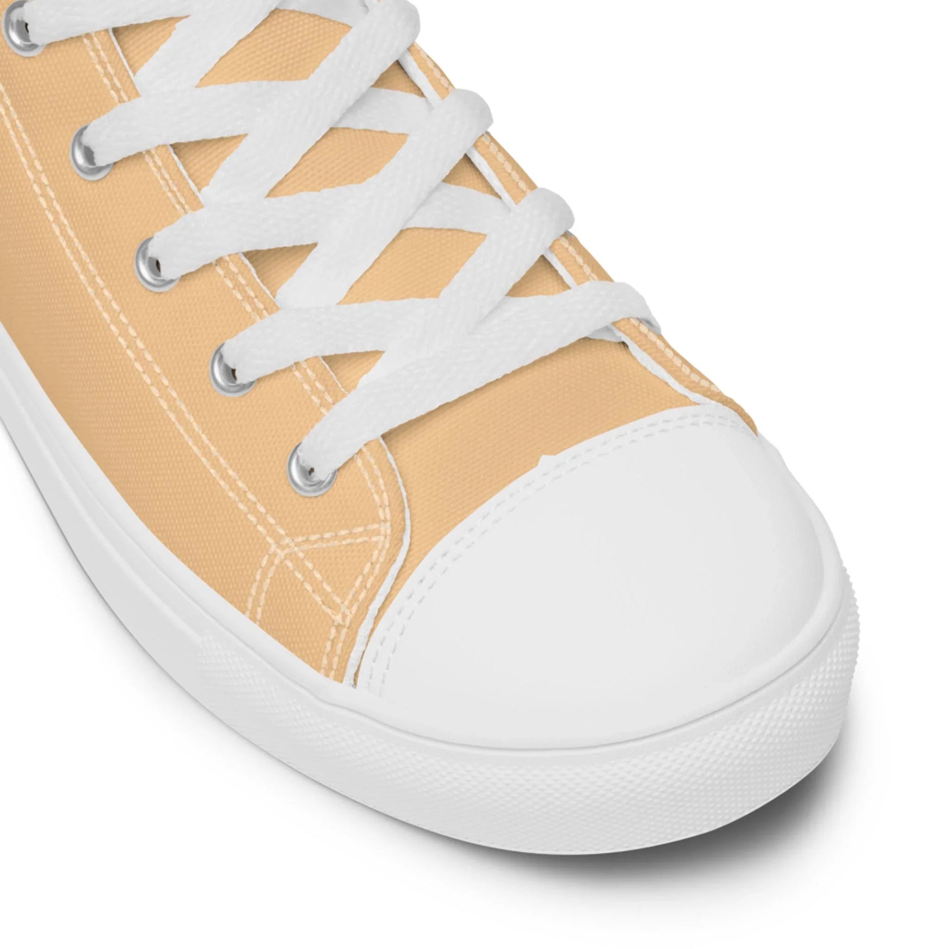Close-up of a beige Mambí canvas sneaker with white laces, a white rubber toe cap, and white stitching, shown against a plain white background.