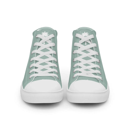 A pair of mint green high-top sneakers with white laces and soles, viewed from the front. A subtle white palm tree graphic and the word Mambí are visible on the tongue of each shoe.