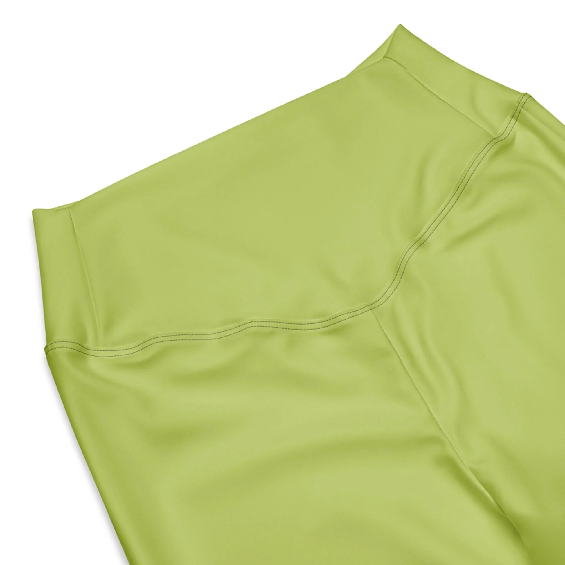 A close-up of the high waist and upper section of Printful Carolina Flared Performance Leggings for women in light green, highlighting smooth fabric and detailed stitching against a white background.
