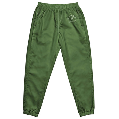 Green satin jogger pants with an elastic waistband and cuffs, two side pockets, and white Mambí text on the left thigh. The fabric has a slight sheen, giving the pants a stylish appearance.