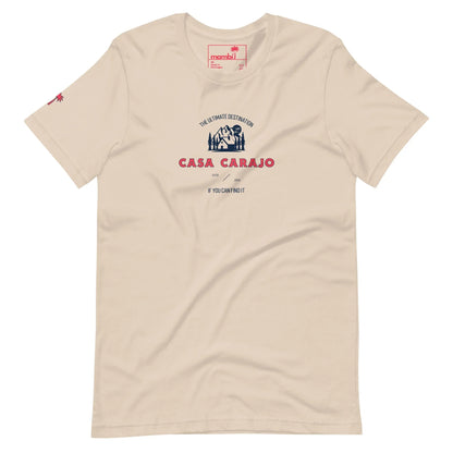 Beige t-shirt with a graphic reading CASA CARAJO in bold red letters, a small hut illustration, and the phrase THE ULTIMATE DESTINATION above. Mambí-inspired design adds character. Small red graphic on the left sleeve.