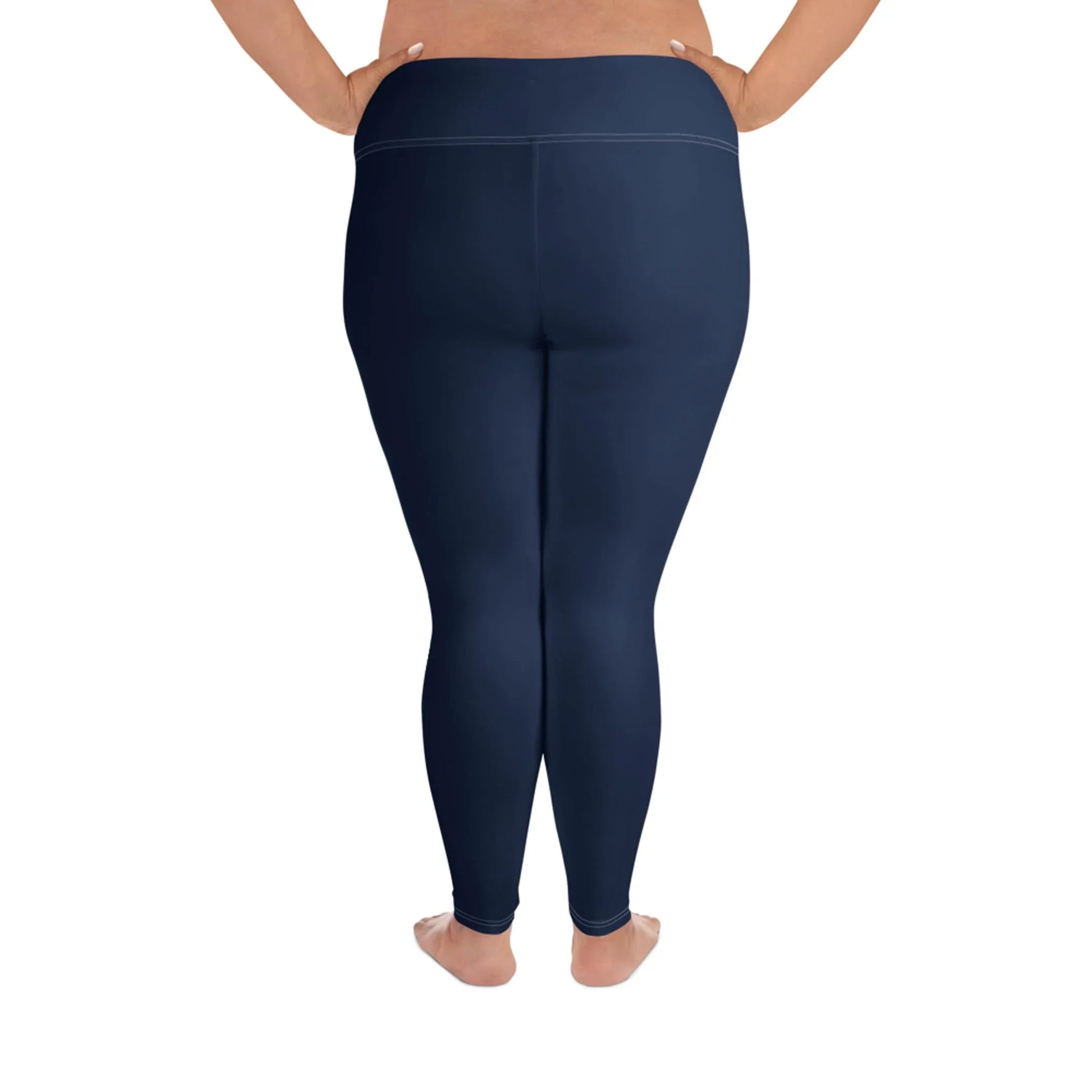 A person standing barefoot shown from the back, wearing high-waisted, navy blue Mambí leggings. The background is white.
