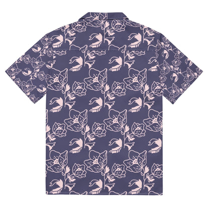 Short-sleeve button-up shirt with a dark purple background and light pink floral and cat face pattern, shown from the back. A unique Mambí style adds flair to this playful design.