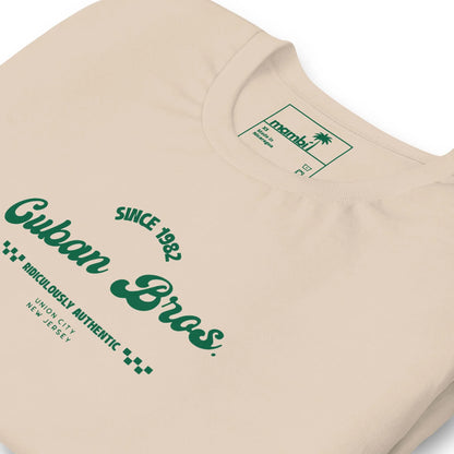The Printful Cuban Bros Graphic Tee | Unisex features beige fabric, green text with “Since 1982” and “Union City, New Jersey,” and a palm tree logo—ideal for entrepreneurs who appreciate standout Neighborhood Collection designs.