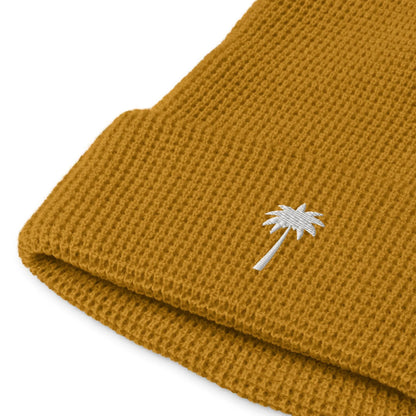 Mustard yellow knitted beanie with a folded brim, featuring a small white embroidered palm tree design near the edge—a subtle nod to Mambí style.