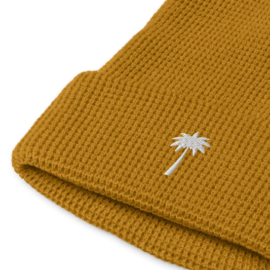Mustard yellow knitted beanie with a folded brim, featuring a small white embroidered palm tree design near the edge—a subtle nod to Mambí style.