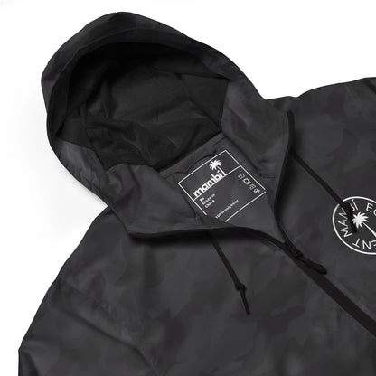 A black camo hooded jacket with mesh lining, drawstrings, and a white manahi label inside the collar. A circular palm tree logo with the text Manahi Equipment and subtle Mambí details appears on the chest.