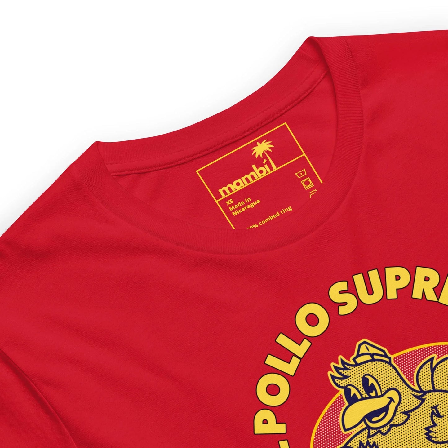 A red t-shirt with a yellow Mambí label inside the collar, featuring a palm tree graphic. The front showcases a partial cartoon chicken and bold EL POLLO SUPR text.