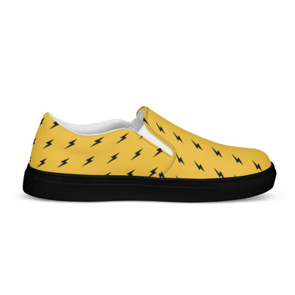 The Electra Handmade Slip-On Canvas Shoes for men by Printful feature a yellow canvas, black sole, white interior lining, and bold black lightning bolt pattern—a standout fashion statement in a comfortable slip-on design.