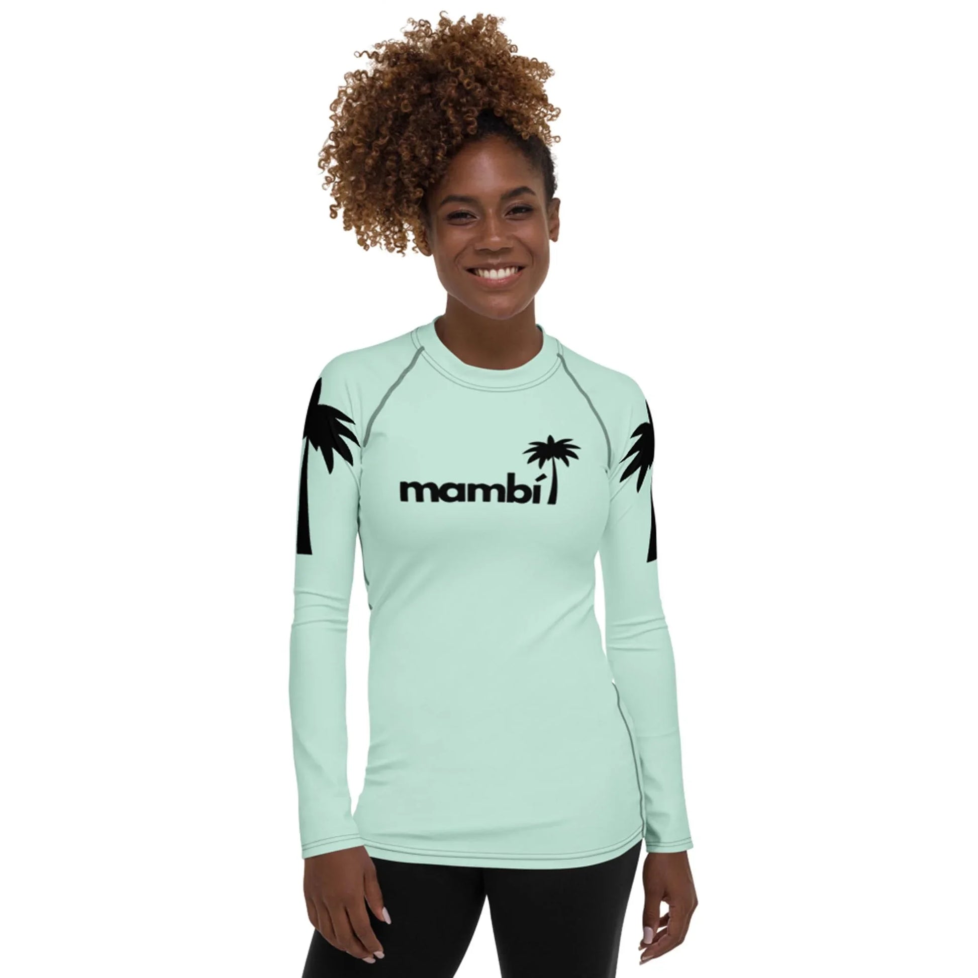 A smiling woman with curly hair models the Printful Ellie Classic Long-Sleeve Rash Guard for women, featuring black palm tree designs, mambi printed on the front, and UPF 50+ protection against a plain white background.