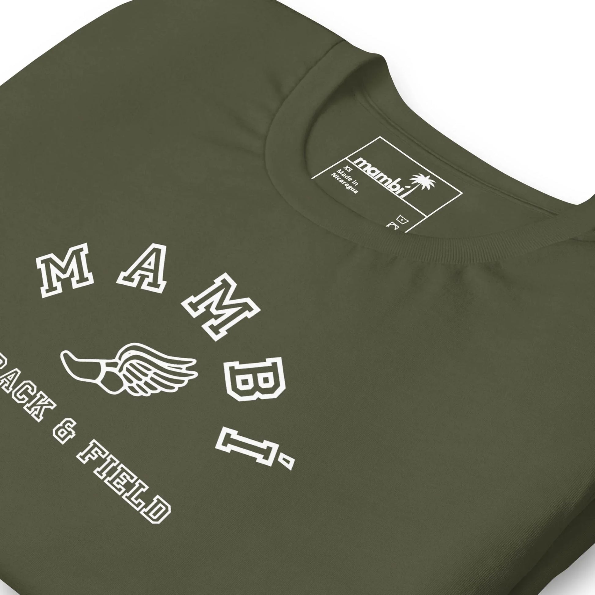 A close-up of an olive green Mambí t-shirt featuring the text MAMBI above a winged foot graphic and TRACK & FIELD underneath. The inside label shows the brand name mambi with a palm tree logo.