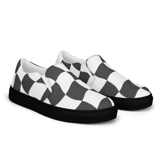A pair of Mambí slip-on shoes featuring a black and white wavy checkerboard pattern on the upper fabric and solid black soles.