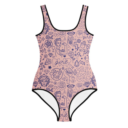 A pink one-piece swimsuit with black trim features Mambí-inspired blue line art illustrations, energetic phrases like Girls Rule and Girl Power, plus images of women, fists, diamonds, hearts, and lightning bolts.