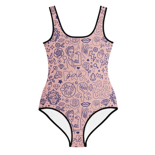 A pink one-piece swimsuit with black trim features Mambí-inspired blue line art illustrations, energetic phrases like Girls Rule and Girl Power, plus images of women, fists, diamonds, hearts, and lightning bolts.