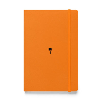 An orange Mambí notebook featuring a small black palm tree illustration in the center of the cover and an elastic band closure on the right side.