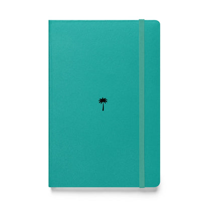 A teal-colored Mambí notebook features a small black palm tree icon in the center and an elastic band closure running vertically along the right side.