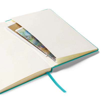 An open Mambí notebook with a teal cover and ribbon bookmark, featuring an inside pocket at the back that holds colorful papers and envelopes.