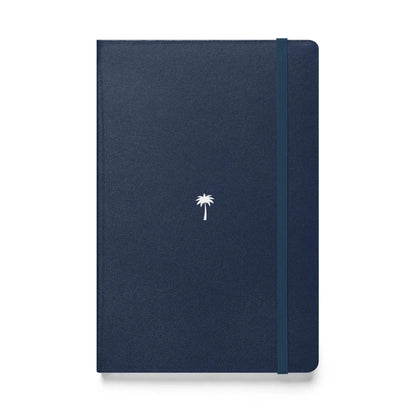 A closed, navy blue Mambí notebook with a small white palm tree design centered on the cover and an elastic band running vertically along the right edge.
