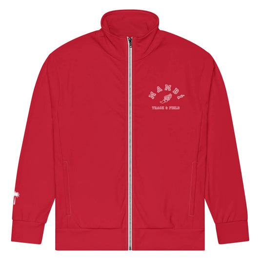 A red zip-up track jacket featuring Mambí white text and a winged shoe graphic on the left chest reading NAMDÊ TRACK & FIELD. A small white palm tree graphic appears on the left sleeve near the wrist.