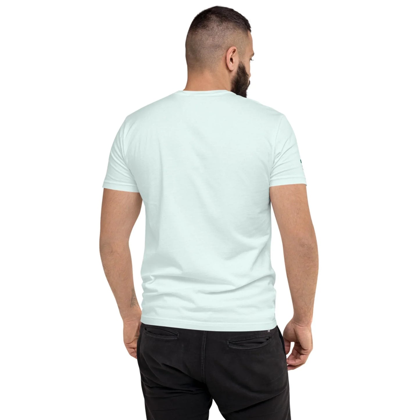 A man with a beard is standing with his back to the camera, wearing a plain light blue Mambí t-shirt and black pants against a white background.