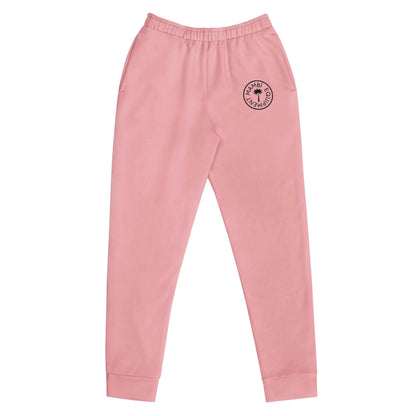 Light pink Mambí jogger sweatpants with an elastic waistband, side pockets, and a black circular logo on the left thigh. The pants feature cuffed ankles and are displayed on a plain white background.