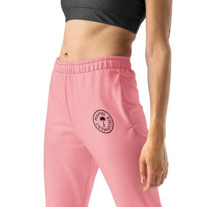 A person wearing a black crop top and high-waisted pink sweatpants with an elastic waistband and a circular Mambí GODDESS logo on the left hip. Only the torso and upper legs are visible.