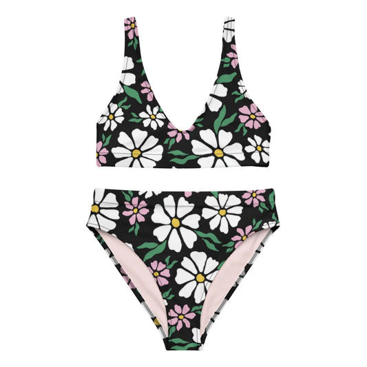 A two-piece Mambí bikini with a deep V-neck top and high-waisted bottom, featuring a bold floral pattern of large white and pink flowers with green leaves on a black background.