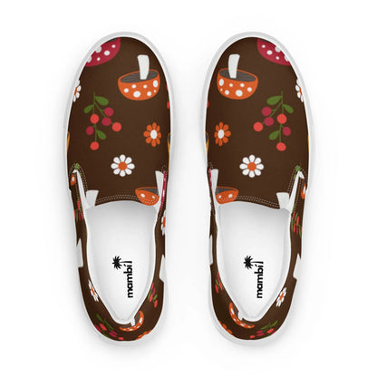 Step out in style with the Mario Handmade Slip-On Canvas Shoes for men by Printful, featuring a brown canvas adorned with vibrant flowers, berries, and orange bowls. The inner soles display the mambil logo with a palm tree icon—perfect for making a statement.