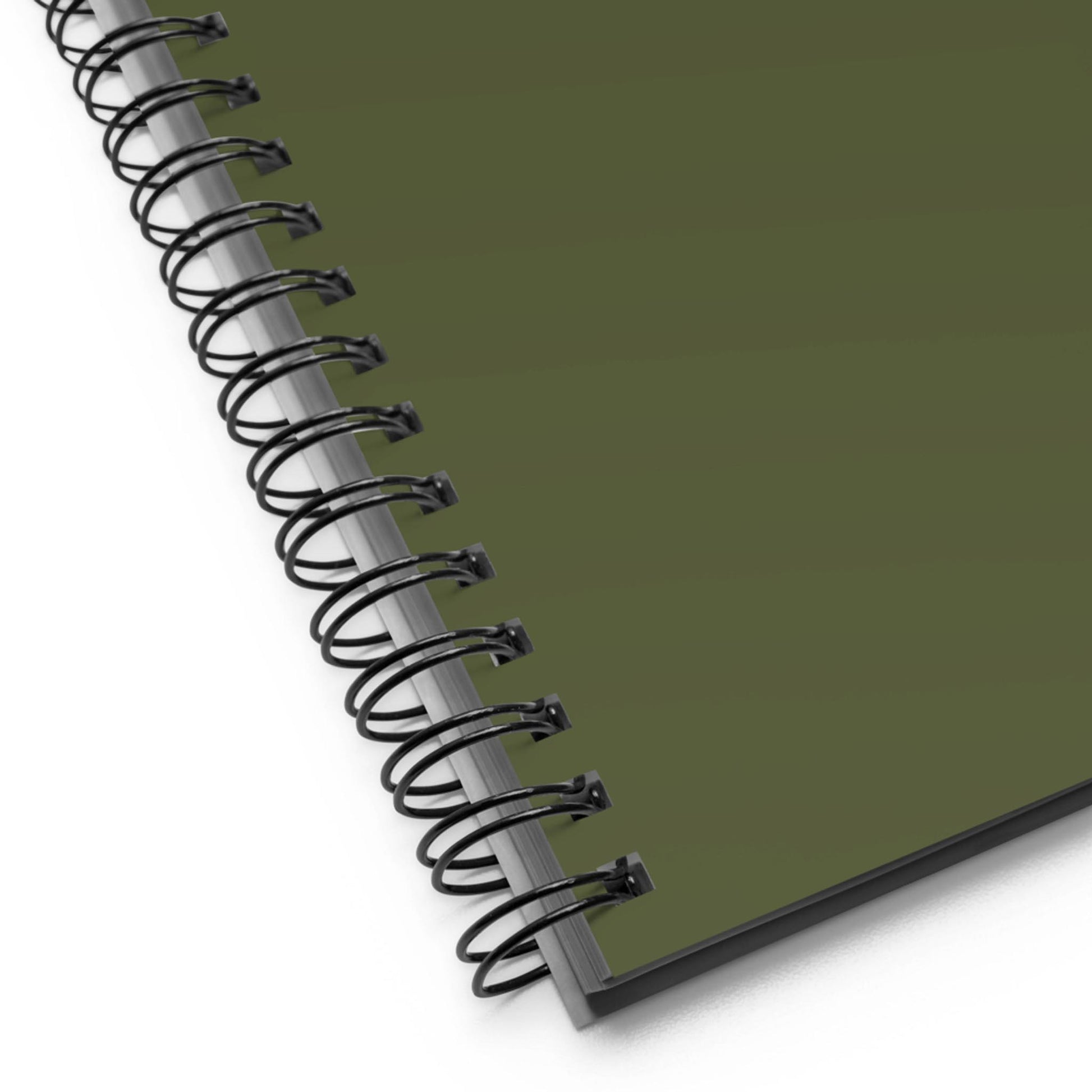 Close-up of the corner of a custom wire-bound notebook with a dark green cover, showing the black metal binding and part of the pages beneath.