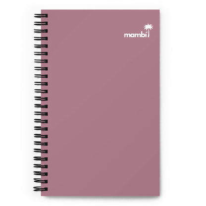 A mauve spiral-bound notebook with a plain cover, featuring dotted pages. The top right corner displays a small white palm tree icon and the brand name mambi in white text—a perfect daily companion notebook.