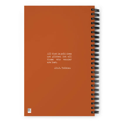An orange wire-bound notebook featuring a quote in white text: All that is gold does not glitter. Not all those who wander are lost. – J.R.R. Tolkien.