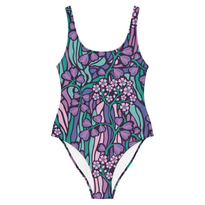 The Micaela One-Piece Swimsuit by Printful is a chic silhouette crafted from stretchy fabric, showcasing illustrated flowers and leaves in purple, pink, and teal on a white background.
