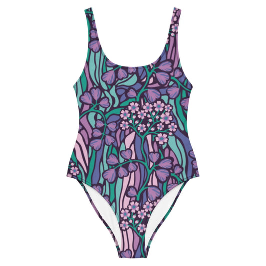 The Micaela One-Piece Swimsuit by Printful is a chic silhouette crafted from stretchy fabric, showcasing illustrated flowers and leaves in purple, pink, and teal on a white background.