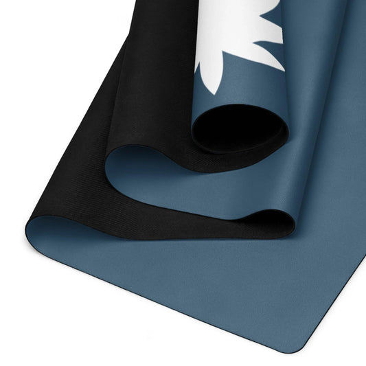 A close-up view of two rolled yoga mats, one black and one blue, with the blue mat featuring a partial white leaf design in the corner, from Mambí.