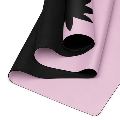 A close-up view of a Mambí yoga mat with a soft pink surface and black design accents, highlighting the layered texture and curved edges.
