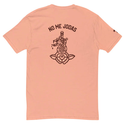 The No Me Jodas Fitted Graphic Tee by Printful features a peach hue, soft cotton fabric, and a bold black graphic of a dagger through a flower with the phrase NO ME JODAS above—perfect for fans of standout mens tees.